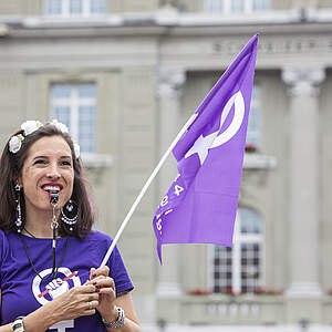 Frau mit Frauenstreikfahne und Trillerpfeife