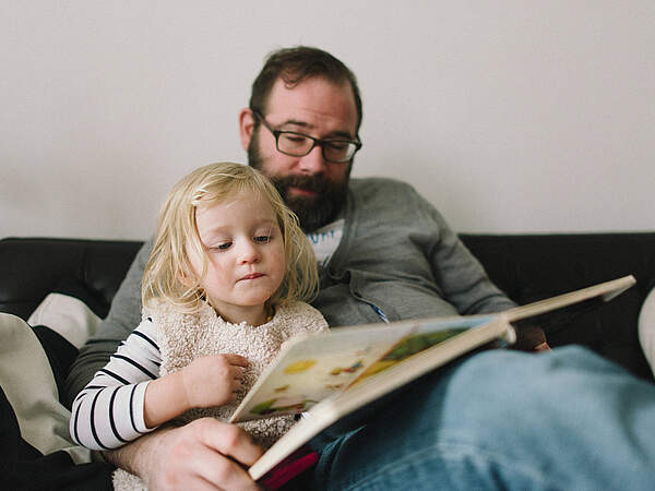Mann liest einem Kind vor